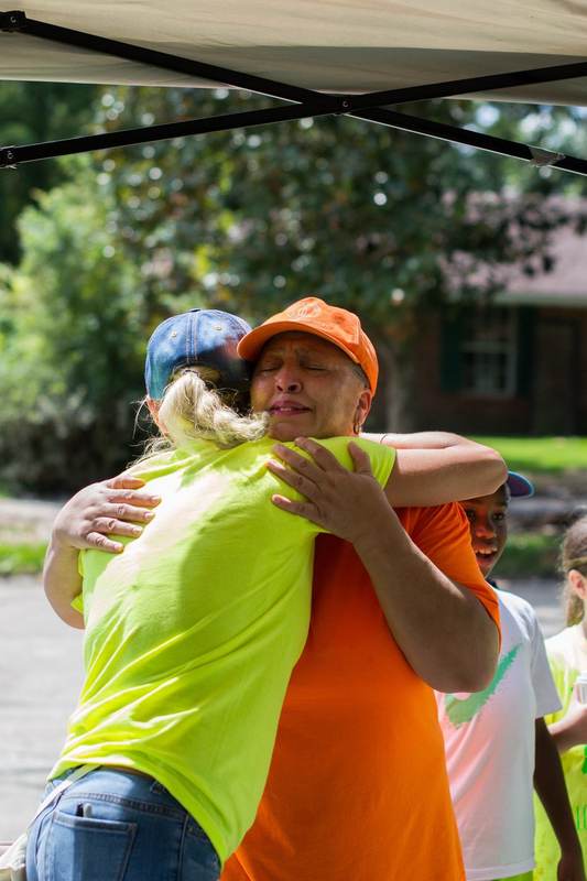 Two people in safety vests sharing a hug.