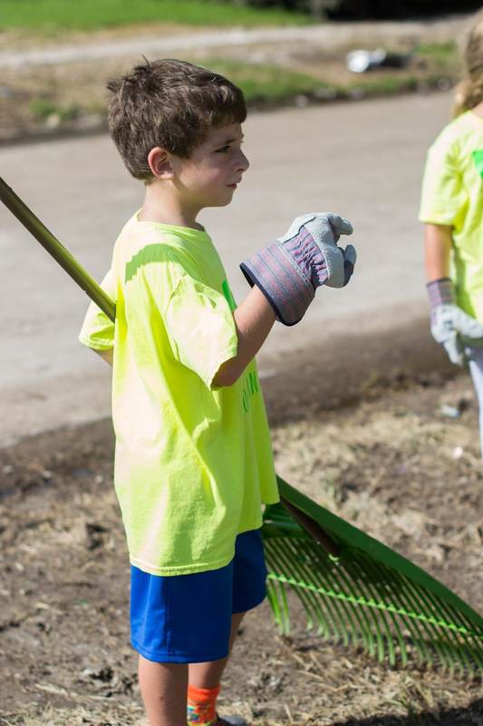 A child with a rake and work gloves.