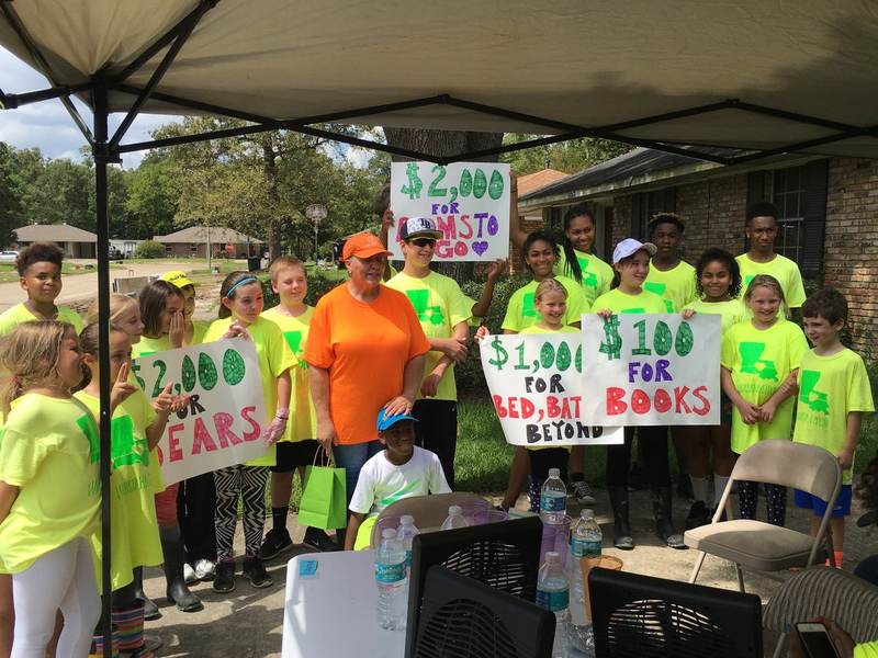 Volunteers under a tent with signs for books and school supplies.