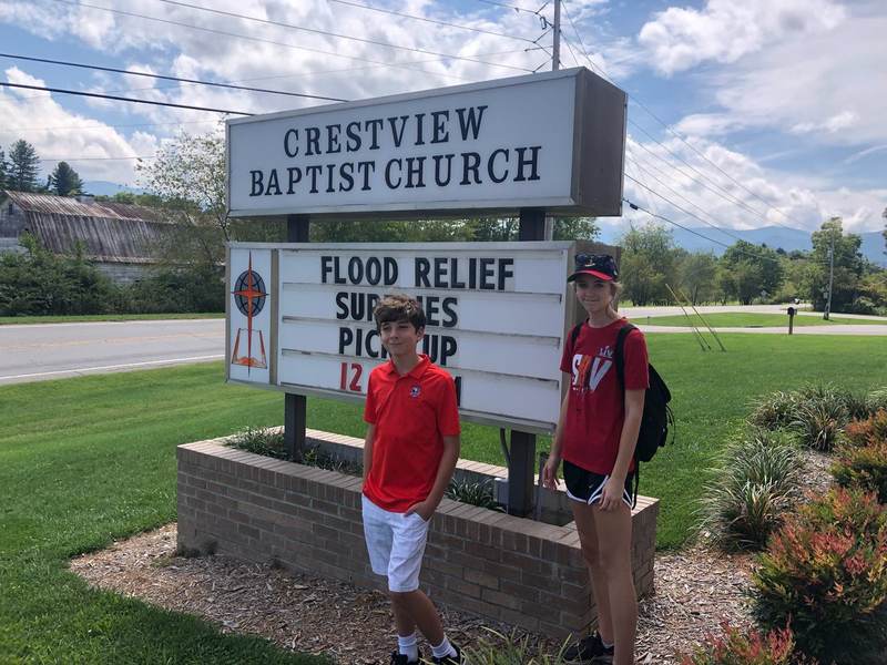 A child in front of a church flood-relief sign.