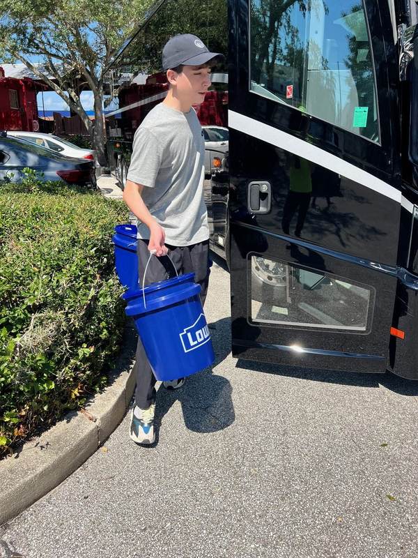 A volunteer carrying a bucket from a vehicle.