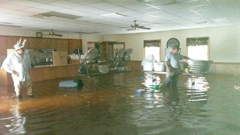 Two people standing in a flooded community room.