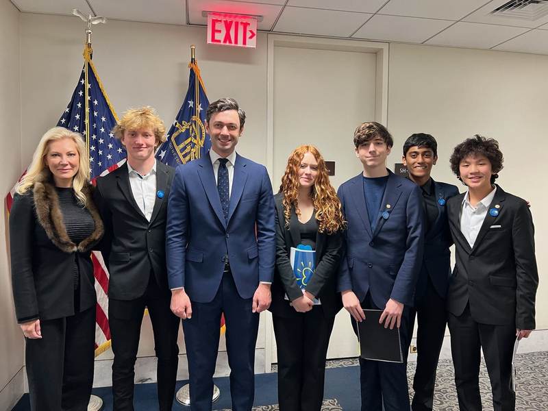 Students with officials in front of an American flag.