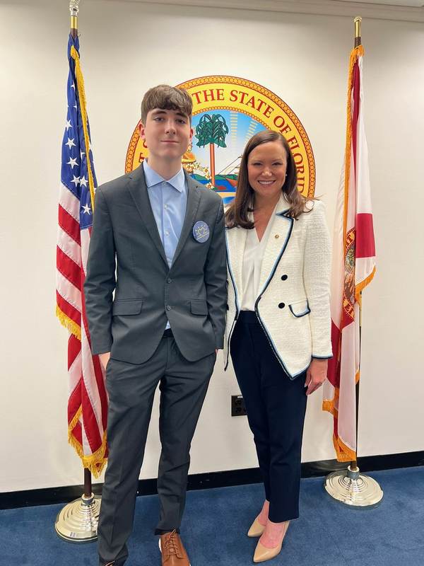 Two people beside the Florida and United States flags.
