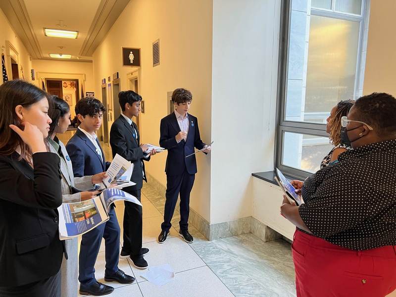 Students speaking with an official in a Capitol hallway.