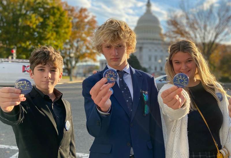 Students holding medals in front of the U.S. Capitol.
