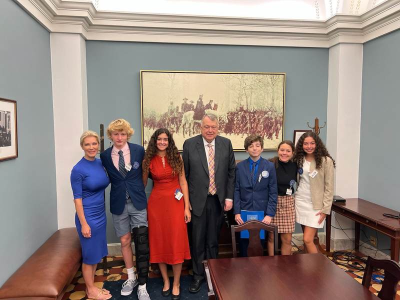 Students with an official in a formal office.