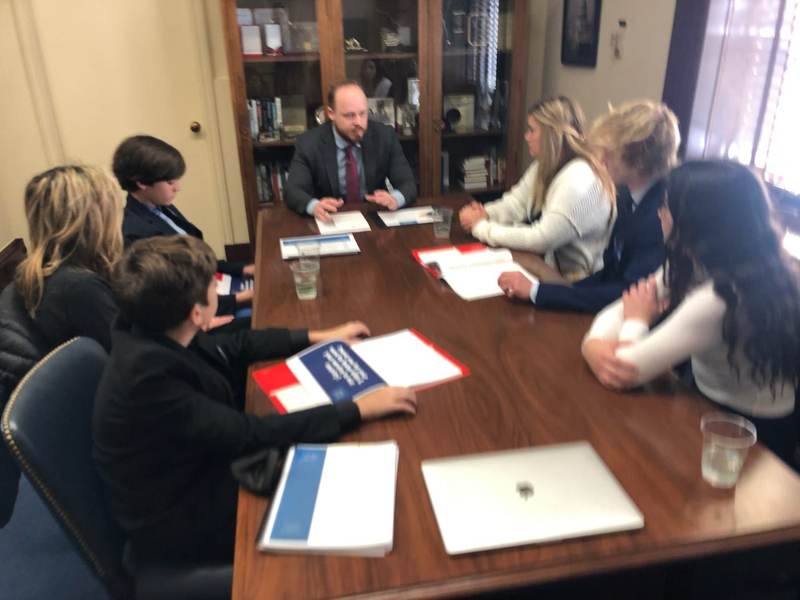 A meeting around a conference table with folders.