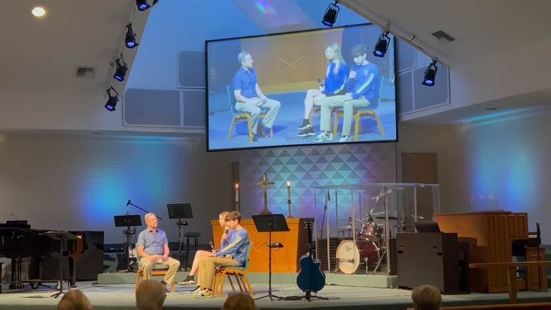 A stage talk, with the conversation shown on the screen behind the speakers.