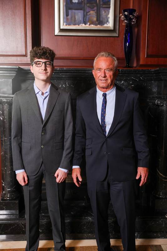 A portrait with an official in front of a fireplace.