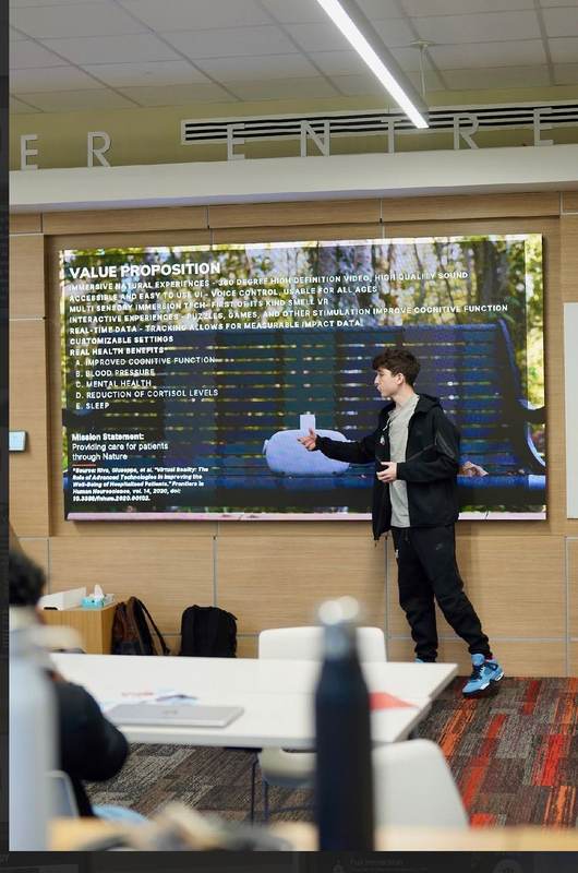A speaker presenting beside a large screen at an EBIT session.